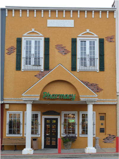 Two story yellow building with two white columns by the door.  There is a green sign above the door that says 